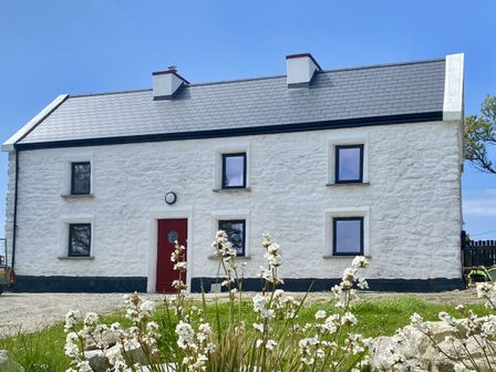 A house with a red door and windows at Nead na bhFáinleog (Swallows’ Nest) Claddaghduff, County Galway
