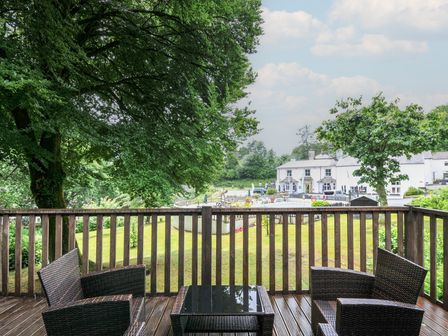 A deck with chairs and a table overlooking a garden at Valley Lodge 2 Callington