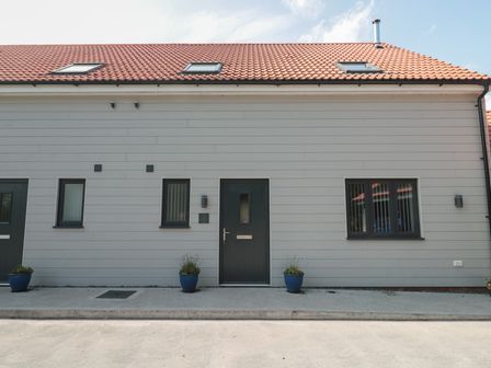 An exterior view of a modern house with a door and windows at 3 The Stables Highbridge