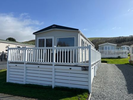 A mobile home with a deck and gravel path at 8 Puffin Way Llwyngwril
