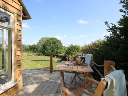 An outdoor seating area with a table and chairs at Squirrel's Drey Chapel Lawn near Clun