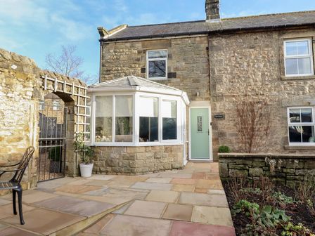 An outdoor area with a conservatory and pathway at Linn Cottage in Hexham
