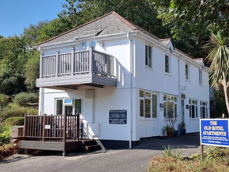 An exterior view of the Old Hotel Apartments with a balcony and plants at Tater-Du in Porthcurno near Land’s End