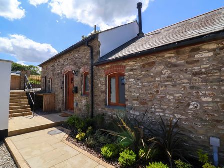 An outdoor view of a cottage with stone walls and garden at Hedgehog Highway Parkham