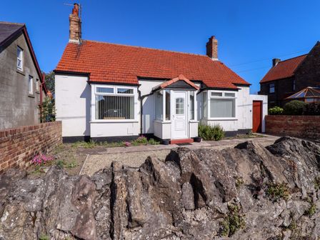 A house with a garden and pathway at Godetia Cottage in Seahouses