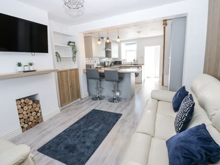 A living room with a television, sofa and kitchen island at Keekle Terrace in Cleator Moor