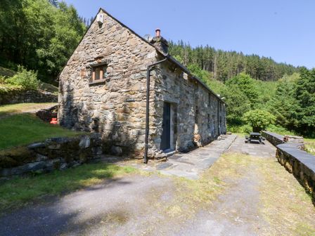 A stone building with windows and a door in an outdoor area at Ty Newydd
