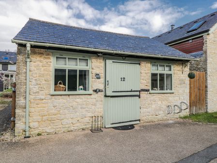 An exterior view of a cottage featuring a stone wall and slate roof at Firefly Cottage
