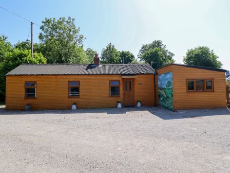 A wooden house with a mural and a gravel area at Haven in Lloc near Holywell