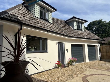 A house exterior with garage doors and flower pots at 8 Church Road Ferndown