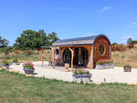A wooden cabin with outdoor seating and flower planters at Bugley Pools Hideaway in Bugley near Gillingham