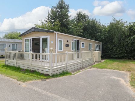 A mobile home with decking and grass at 17 Castle Walk in Great Yarmouth
