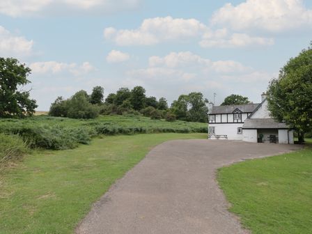 An outdoor view of a house with a driveway and trees at Hillside Cottage in 