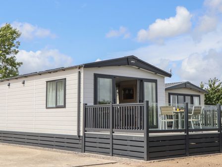 A mobile home with a deck and dining area at Maple Lodge in Teigngrace near Kingsteignton