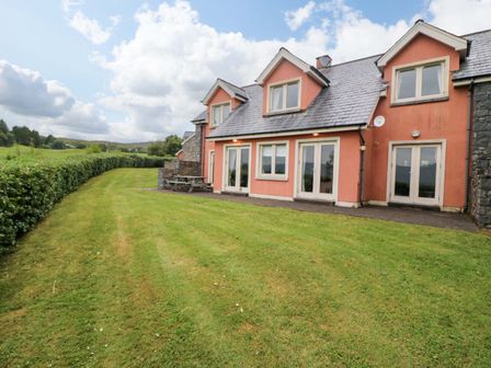 A house with a patio and grass yard at 25 Ring of Kerry Holiday Cottages in Kenmare