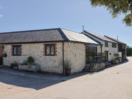 An outdoor view of a stone building with windows and planters at The Sundowner in Wyke Nr. Axminster