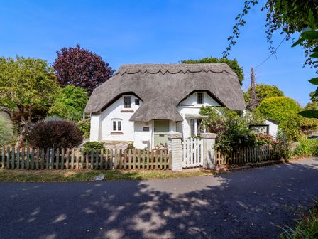 A cottage with a thatched roof and a garden at Smugglers Cottage in Barton On Sea