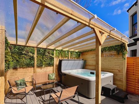 An outdoor area with a hot tub and seating at Clarence House in Llandudno
