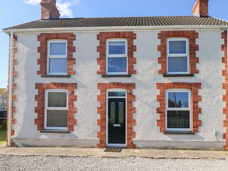 A house with brick detail and a green door at Hawthorns in Swansea