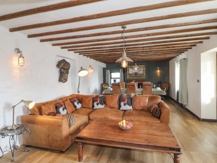 A living room with a sofa and dining area at Clawddcam in Mathry