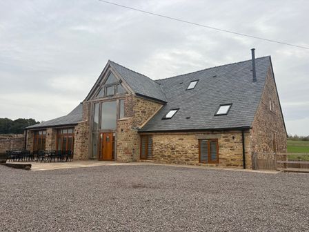 A house with a slate roof and wooden doors at Two Parks Barn Upton Bishop near Ross-On-Wye