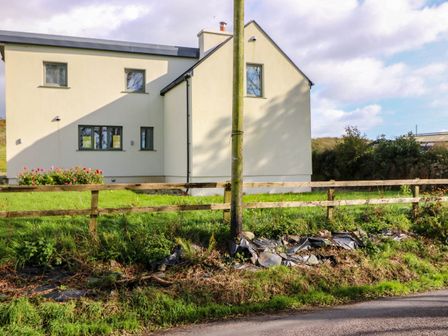A house exterior with a fence and grass at Knocknanuss in Ballinascarty, County Cork