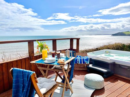A patio with a table set for breakfast and a hot tub at Crows Nest Dawlish