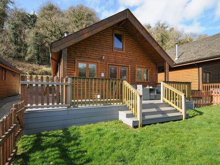 A log cabin with a deck and fence at Trebah in St Breward