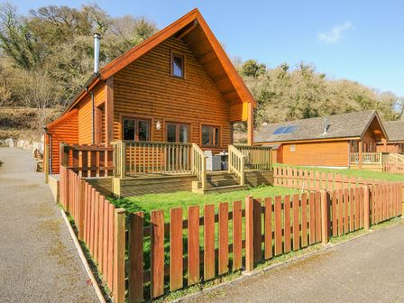 A wooden cabin with a deck and fence at Polzeath St Breward