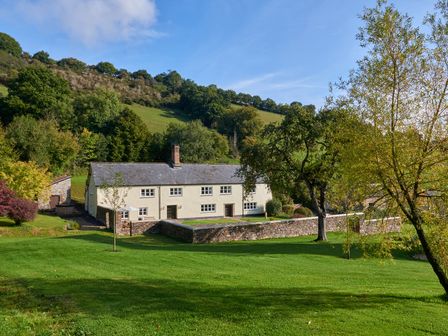 A house surrounded by grass and trees at Holwell Farmhouse in Bampton
