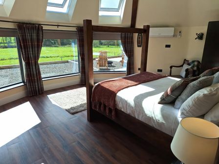 A bedroom with a bed and large windows at Y Cwlwm - The Celtic Knot near Lampeter