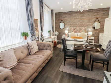 A living room with a sofa, table, and bed at The Railway Apartment in Hexham
