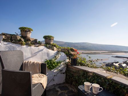An outdoor patio with a chair and cups at The Ingle in Barmouth