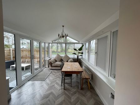 A conservatory with a table and chairs and a sofa at Dolwen in Caernarfon