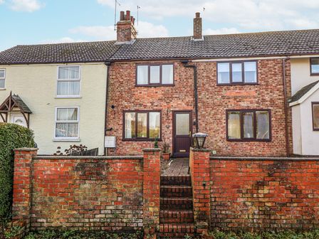 A brick house with steps and fence at Forget Me Not Cottage in Roos