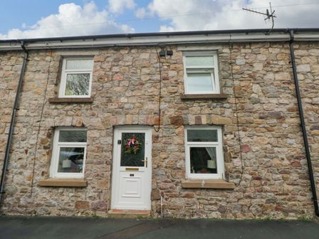 A stone exterior with windows and door at Tawe Cottage in Swansea