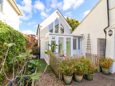 A garden with a conservatory and potted plants at Cherry Pip in Charmouth