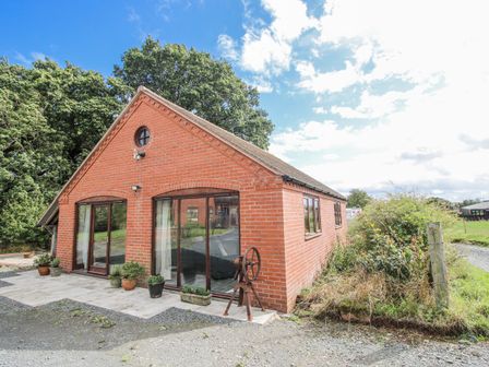 A brick building with large windows and garden area at Bluebell Cottage 