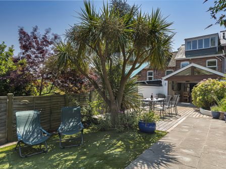 A garden with palm tree and seating area at Shipwrights in Salcombe