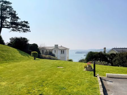 A lawn with a house and water view at Number 2 Ellington Court Apartment Torquay