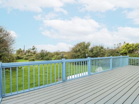 A deck with blue railing and green grass at Harbour Lights in Holyhead