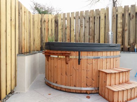 A hot tub with wooden steps in an outdoor space at Barn 5