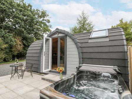 A hot tub and seating area outside a modern structure at Oak View in Rhayader