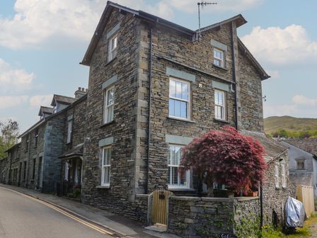 A stone house with windows and a tree at Park View Studio in Ambleside
