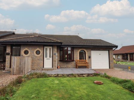 The exterior of a house with a bench and a garage at Nobles Nook in Seahouses