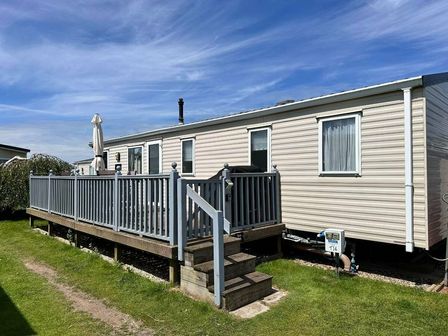 a mobile home with a deck and stairs at Pinewoods Holiday Park - Holiday Accommodation 10664 in Wells-next-the-Sea