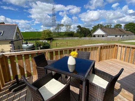 a dining table with chairs on a deck overlooking fields at Silverhill (private land) - Holiday Accommodation 10754 Tavernspite