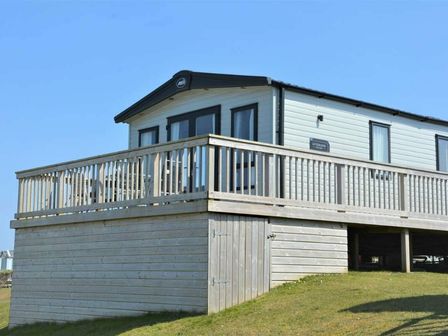 a holiday home with a wooden deck situated on a grassy area at Perran Sands - Holiday Accommodation 11264, Perranporth
