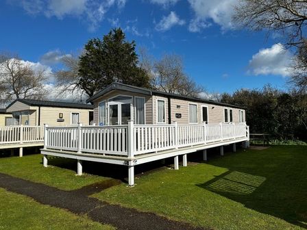 a holiday home with a deck and green lawn at Kiln Park Holiday Park - Holiday Accommodation 11309 in Tenby