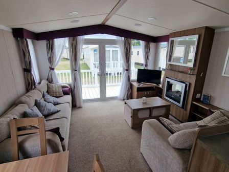 a living room with a television and sliding doors leading to a patio at Seashore Holiday Park - Holiday Accommodation 11473, Great Yarmouth